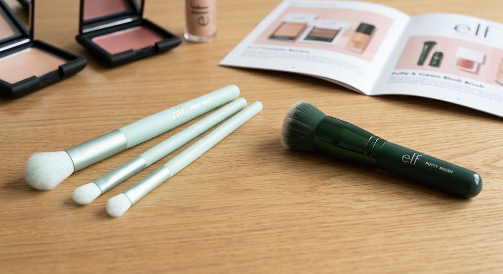 e.l.f Mint Melt eyeshadow brush set and Putty blush brush displayed on a wooden desk beside open review magazine.