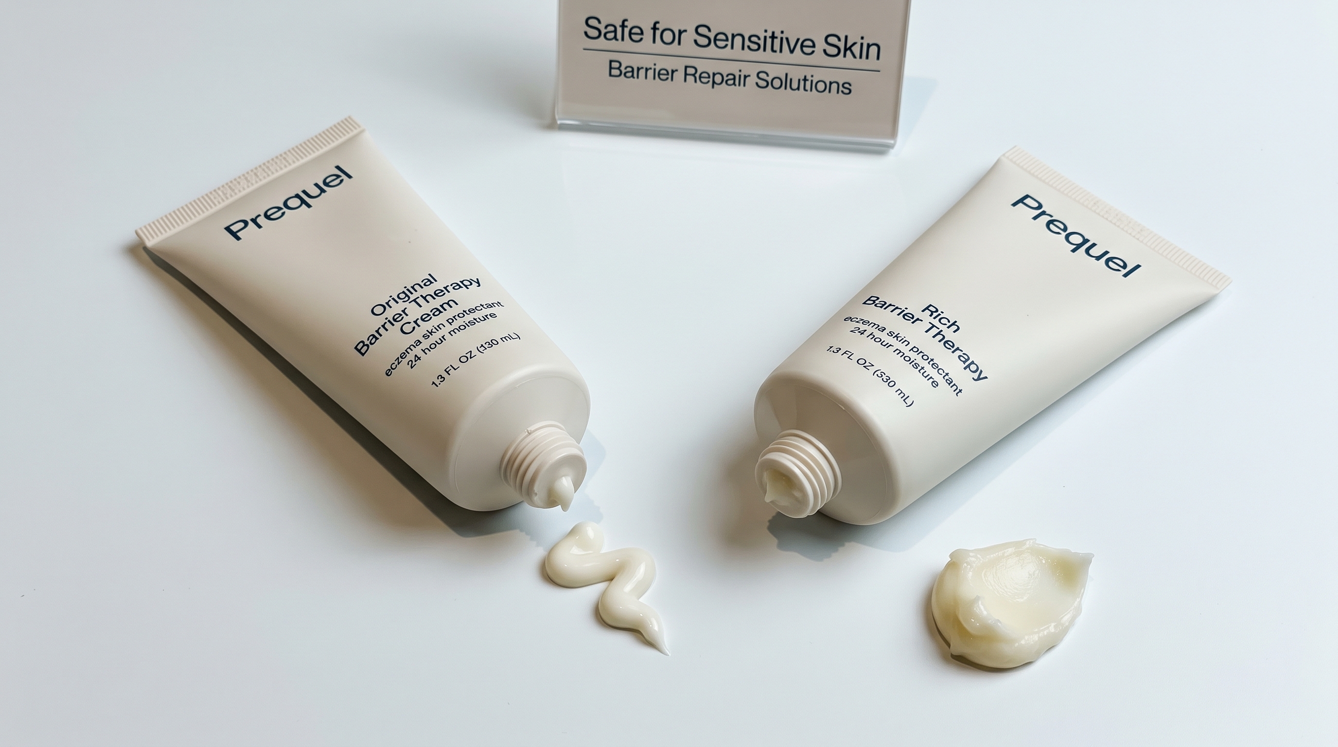 Two Prequel Barrier Therapy cream tubes resting on a white surface, each displaying a squeeze of cream beside it.